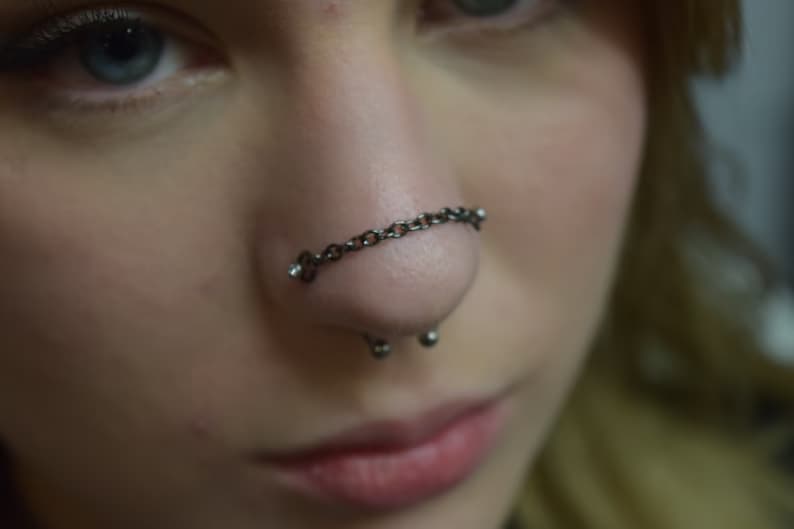 Double nostril piercing with a nose chain