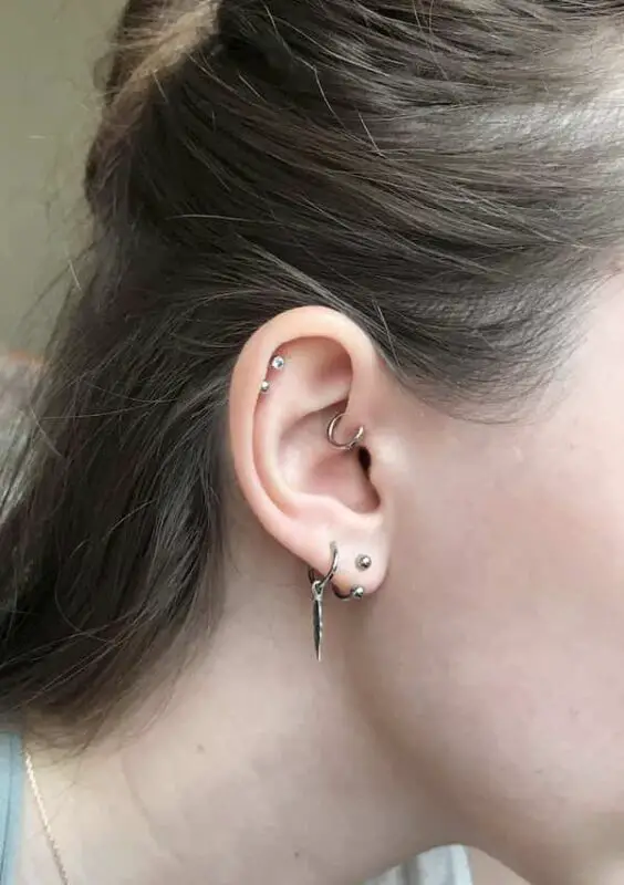 This is a stylish combination of piercings that is both versatile and edgy. The helix piercings can be styled with studs, hoops, or tiny charms, while the forward helix piercings can be styled with studs, hoops, or tiny charms